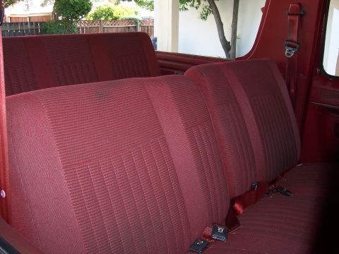 1991 Ford Bronco - Rear interior view of a 1991 Ford Bronco, showing the red fabric seats and seatbelts.