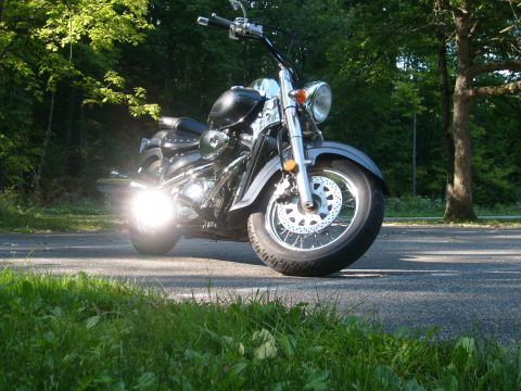 1993 Ford Bronco - A black motorcycle with chrome details sits on a paved surface, surrounded by greenery and trees.