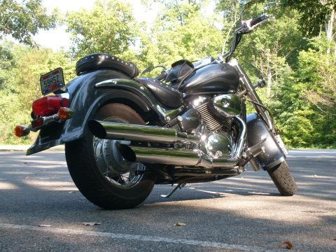 1993 Ford Bronco - A motorcycle is parked on a paved surface with trees visible in the background.