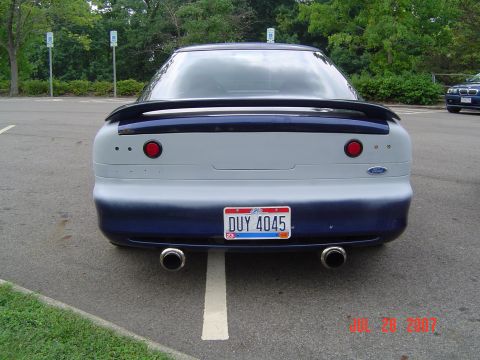 1993 Ford Probe - The rear of a two-tone Ford Probe is parked in a lot, showing its license plate and exhaust pipes.