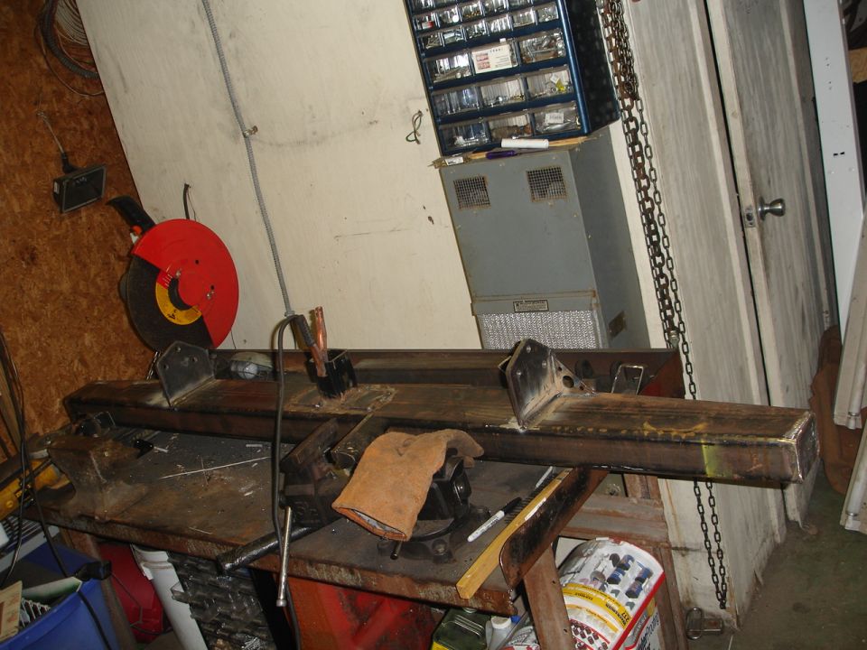 Fabricated steel bumper on workbench with chop saw and welding equipment nearby
