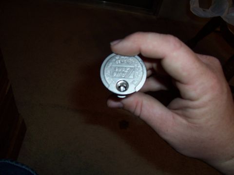2003 Ford Ranger - A hand holds a silver cap with 'Auto 2003' embossed on it, suggesting it might be a part from a 2003 vehicle.