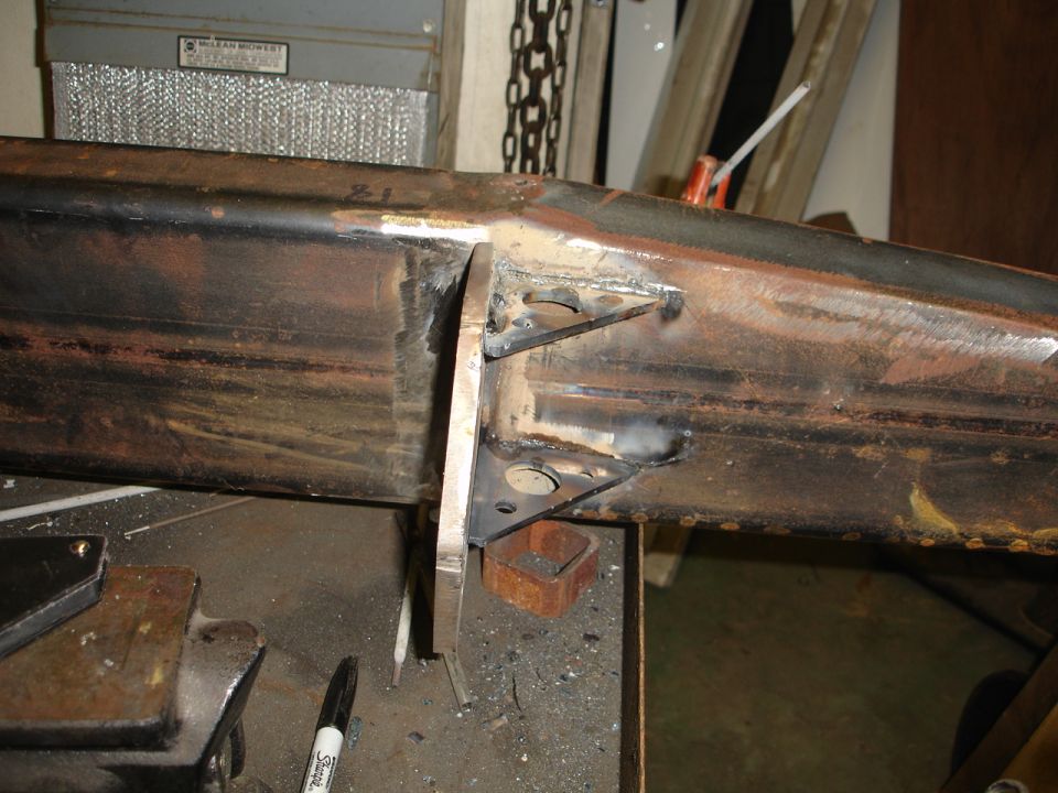 Welding work on a rusty steel frame, possibly part of a vehicle bumper
