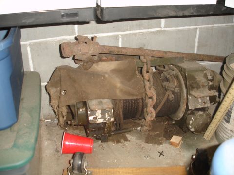 1989 Ford Bronco - A rusty, old winch is covered by a torn cloth and secured with a chain.