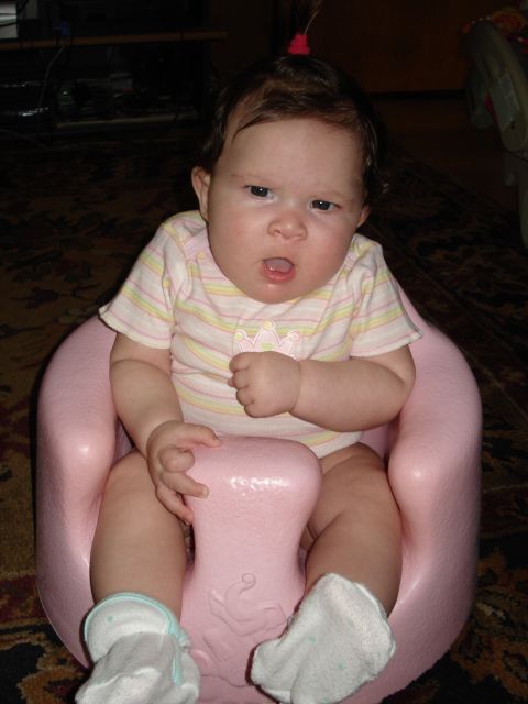 2000 Ford Crown Victoria - A baby sits in a pink seat, looking towards the camera with an open mouth.