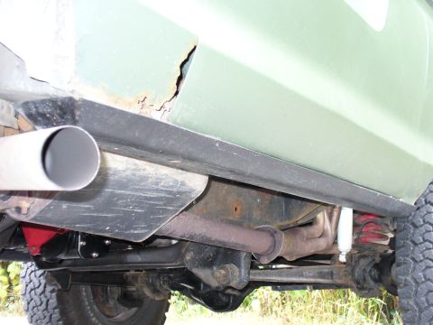 1978 Ford Bronco - Low side-on underbody shot of a light green 4x4 with a large-diameter polished side-exit exhaust tip poking out under the rocker, plus a fl…