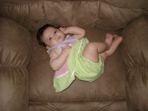 2000 Ford Crown Victoria - A baby relaxes on a plush couch, dressed in a cute outfit.