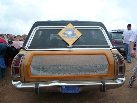 1975 Ford Ranchero - Rear view of a gold station wagon with wood paneling, a Pikes Peak sign in the rear window and a California license plate.