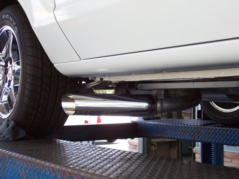 1978 Ford Mustang II - The underside of a white vehicle shows a shiny exhaust system and a tire on a car lift.