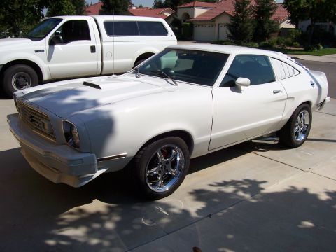 1978 Ford Mustang II - This white coupe, likely a 1975 model, is parked in a driveway next to a pickup truck.