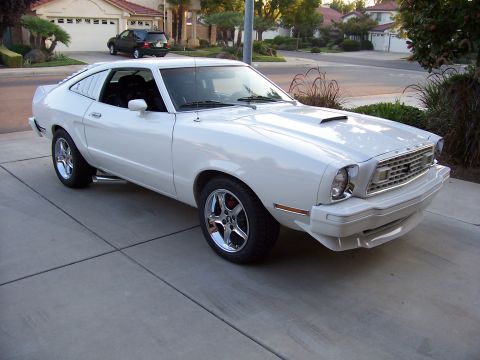 1978 Ford Mustang II - A white coupe with distinctive rear window louvers is parked in a suburban driveway.