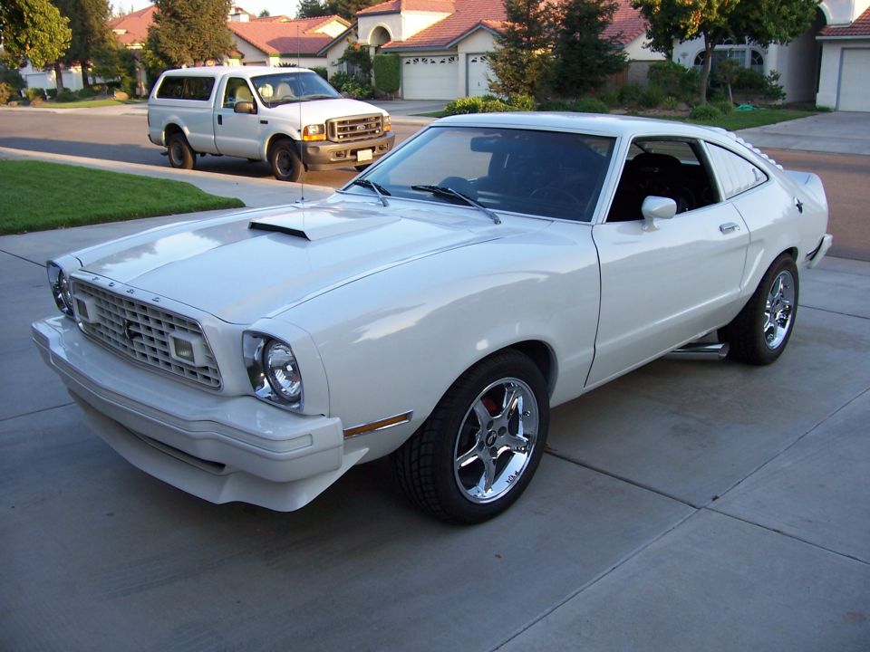 White 1978 Ford Mustang II coupe with hood scoop and chrome wheels