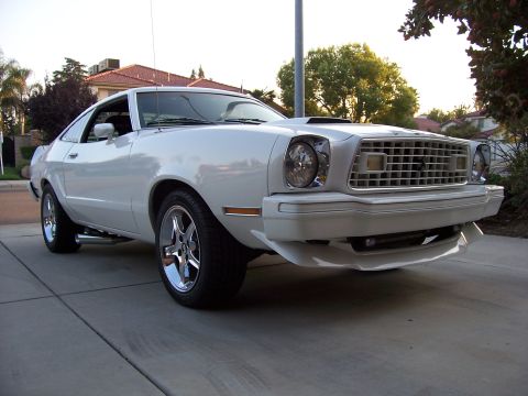 1978 Ford Mustang II - This white coupe features a distinctive grille and a hood scoop, parked on a suburban driveway.