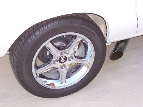 1978 Ford Mustang II - Close-up of a chrome wheel and exhaust pipe on a white vehicle.