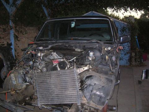1985 Ford Bronco - The front end of a disassembled 1987 Ford Bronco is visible, with its engine and radiator exposed.