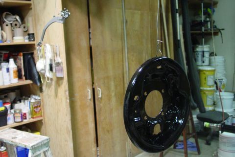 1993 Ford Bronco - A freshly painted brake dust shield hangs in a garage, ready for installation.
