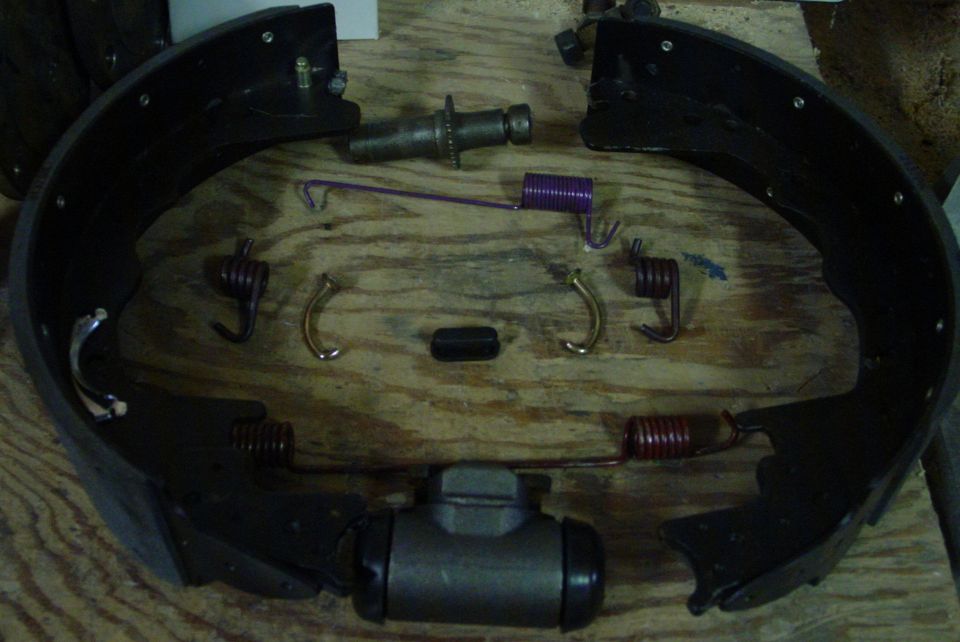 Brake drum hardware kit with springs, shoes, and wheel cylinder on a wooden surface