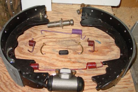 1993 Ford Bronco - A disassembled brake shoe and hardware kit is shown, including springs, a wheel cylinder, and brake shoes.