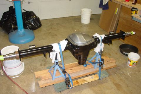 1993 Ford Bronco - A black rear axle assembly is supported by jack stands and wooden blocks in a garage setting.