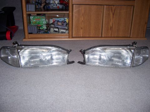 1987 Volkswagen Golf - Two car headlights are displayed on a carpeted floor in front of a wooden cabinet.