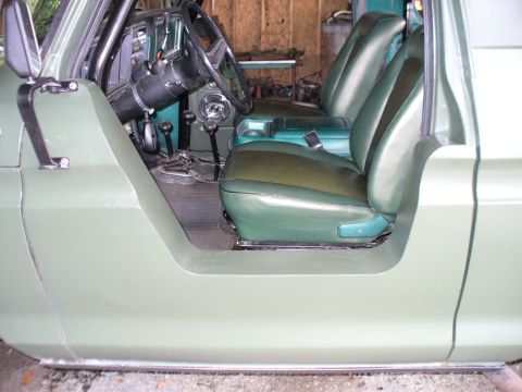 1978 Ford Bronco - The interior of a vintage SUV features green vinyl seats and a dashboard with manual transmission controls.