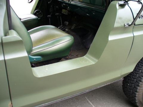 1978 Ford Bronco - The interior of a vehicle is shown, focusing on the driver's seat and the open door frame.