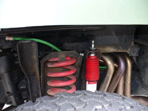 1978 Ford Bronco - Close-up view of the front suspension system, highlighting the red coil spring and shock absorber.