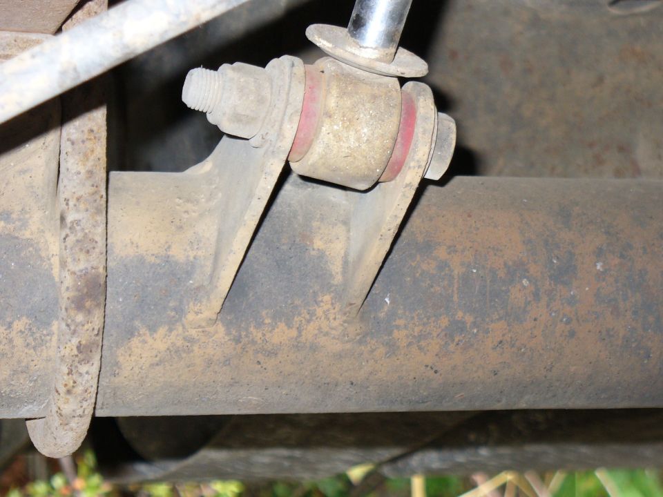 Rear shock mount with red bushings and rusty bracket