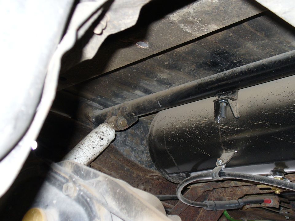 Underside view of a vehicle's rear suspension with a shock absorber and an air tank visible