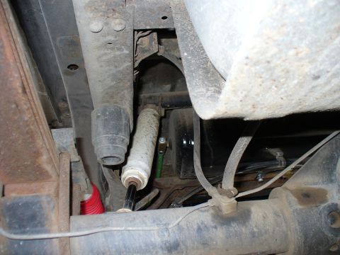 1978 Ford Bronco - Close-up of the rear suspension and undercarriage of a vehicle, highlighting the shock absorber and leaf spring assembly.