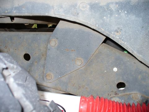 1978 Ford Bronco - Close-up of a vehicle's rear shock mount bracket, showing bolted metalwork and part of a tire.