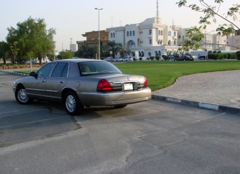 2007 Mercury Grand Marquis - A tan sedan is parked in a lot with a building and grass in the background.