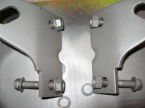 1968 Shelby GT500 - Close-up view of two gray tie down brackets, each secured with bolts and nuts.