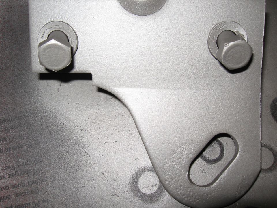 Gray metal bracket with two bolts and a slotted hole, showing some text underneath