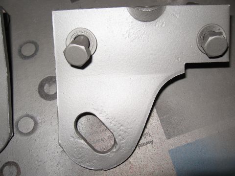 1968 Shelby GT500 - A close-up view of a gray tie down bracket, showing its mounting holes and shape.