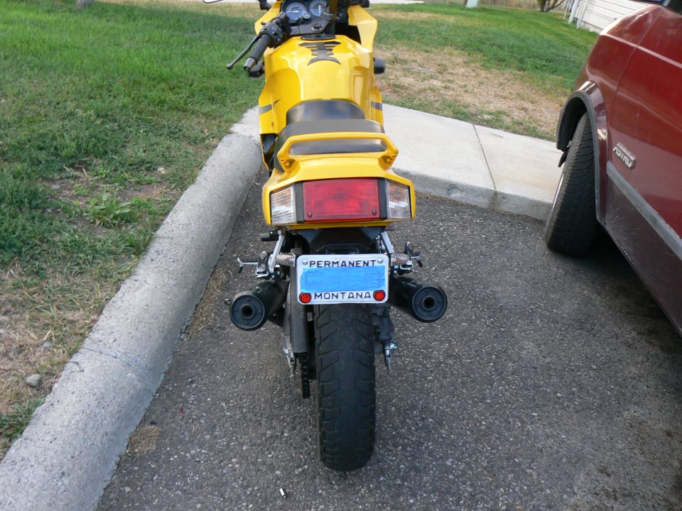 Rear view of yellow sportbike with twin black slip-on exhausts and Montana permanent plate