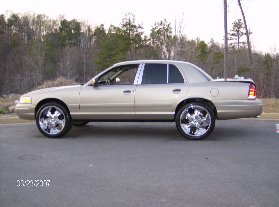 Gold sedan with chrome rims parked on asphalt, trees in background. Date stamp 03/23/2007