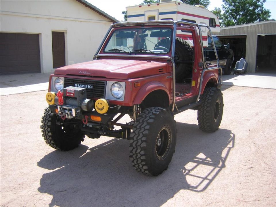 Red lifted Suzuki Samurai on big off-road tires with winch and roll cage