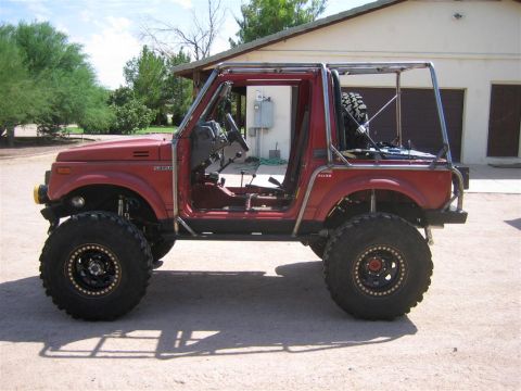 1987 Suzuki Samurai - This modified 1987 Suzuki Samurai features a prominent exo cage and large off-road tires, seen from the side.
