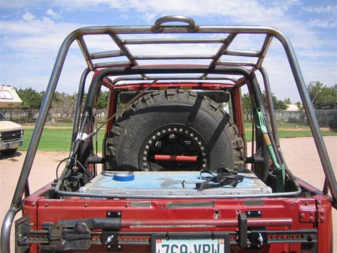 1987 Suzuki Samurai - Rear view of a modified 1987 Suzuki Samurai an extensive external roll cage and a large spare tire mounted on the back.