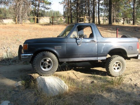 1988 Ford Bronco - This 1988 Ford Bronco is shown in a side profile, parked on a dirt surface with a rock in front of the front tire.