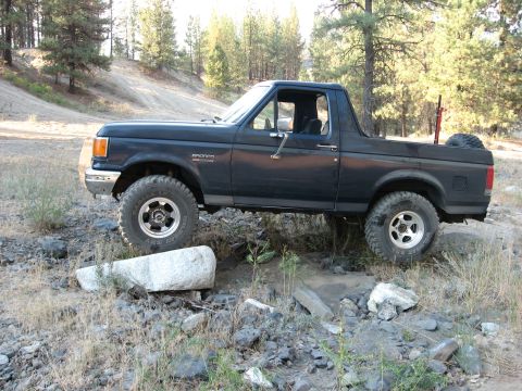 1988 Ford Bronco - This 1988 Ford Bronco is shown off-roading through a rocky, wooded area.