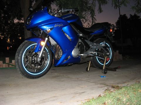 2007 Kawasaki Ninja - A blue Kawasaki Ninja motorcycle is parked outside on a concrete surface with reflective rim tape visible on the wheels.