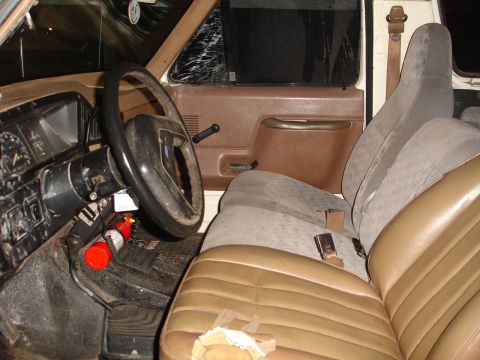 1989 Ford Bronco - The interior of a 1989 Ford Bronco shows a cracked side window and well-used seats.