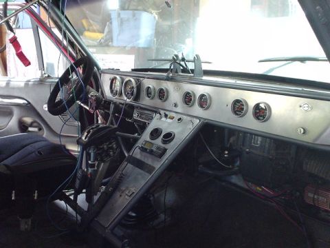 1984 Ford Bronco - Interior view of a vehicle's custom dashboard, numerous gauges and a racing steering wheel.