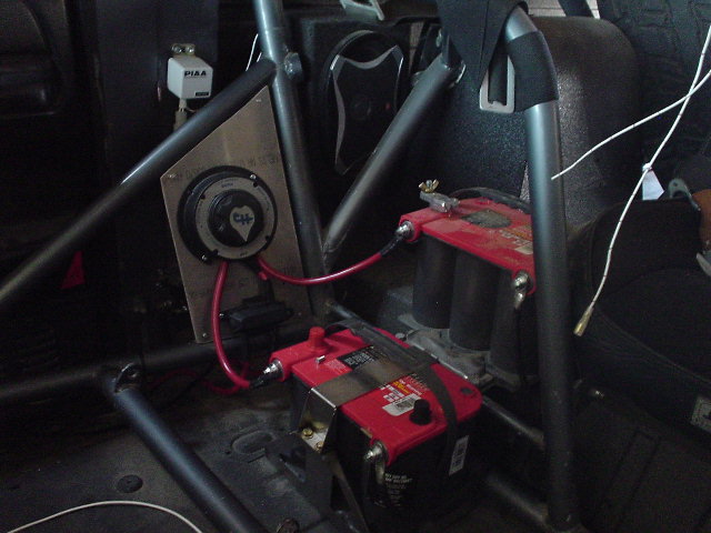 Interior view of dual batteries and a battery disconnect switch with red wiring