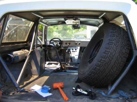 1984 Ford Bronco - The interior of a vehicle shows a spare tire, roll cage, and various tools, suggesting ongoing modifications or repairs.