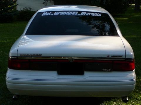 1997 Mercury Grand Marquis - The rear of a white sedan is shown, with a sticker on the window and "Grand Marquis" badging visible.