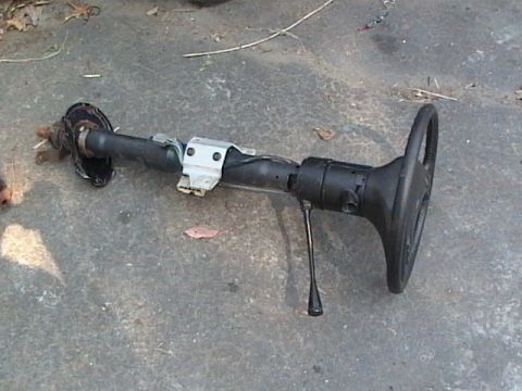 1990 Ford Bronco - A detached steering column and wheel lies on a concrete surface.