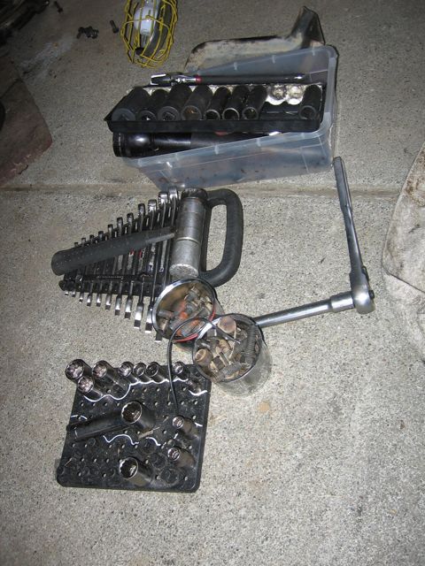 1989 Ford Bronco - Mechanic's tools including sockets, wrenches, and hardware are laid out on a concrete surface.